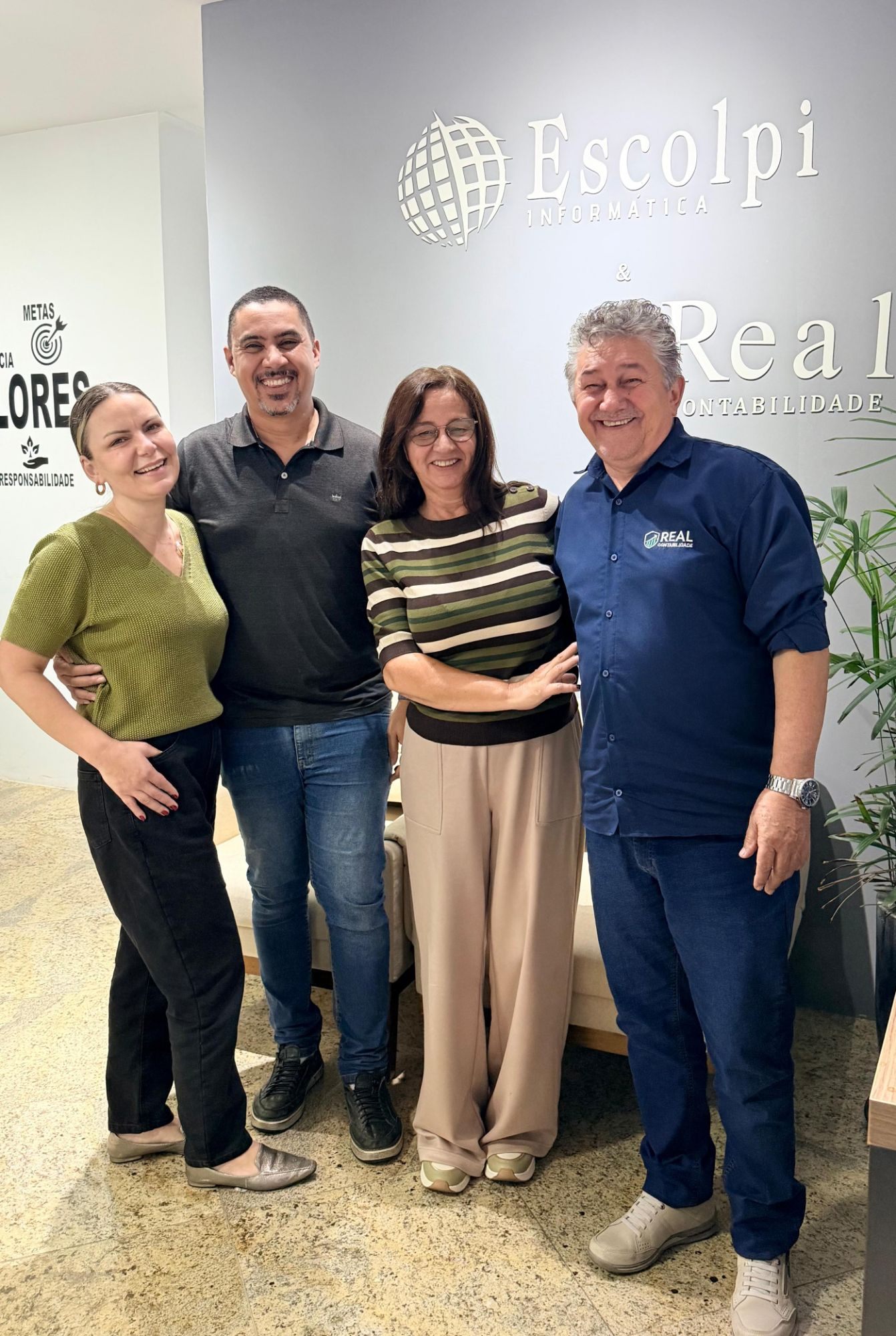 Equipe da Escolpi e da Real Contabilidade BH na recepção, em frente às marcas na parede